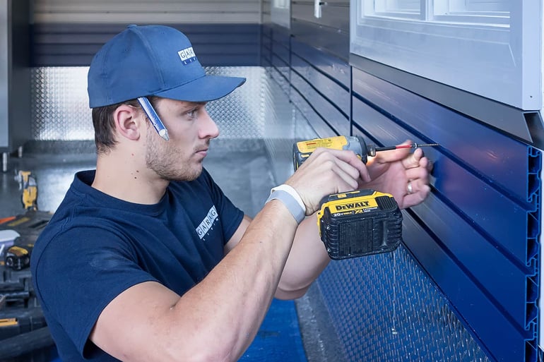 Garage Living installer applying slatwall panels to a garage wall.