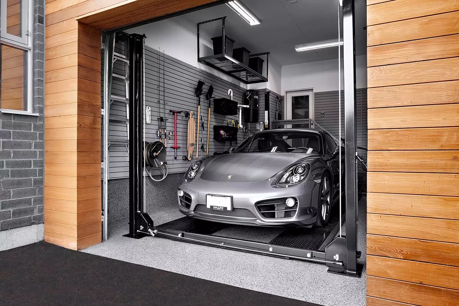 A silver Porsche is being lowered by a car lift in a garage setting - Garage Living