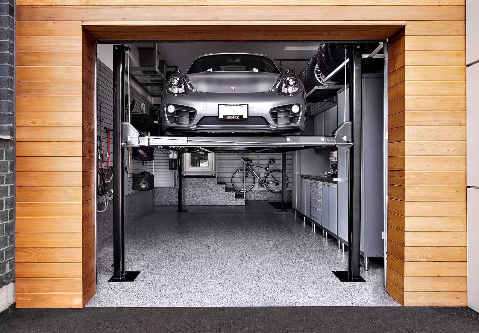 A silver Porsche is being lifted by a car lift - Garage Living